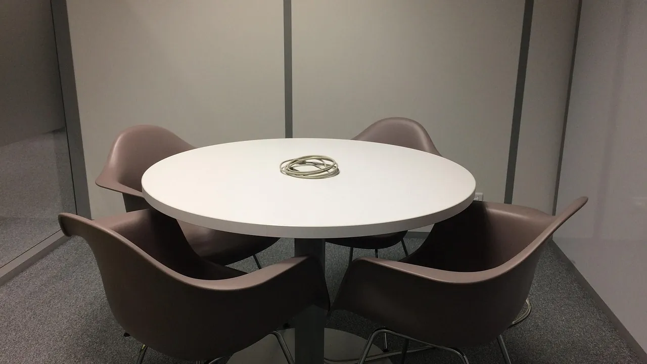 Une petite table ronde entourée de quatre chaises dans une salle de réunion