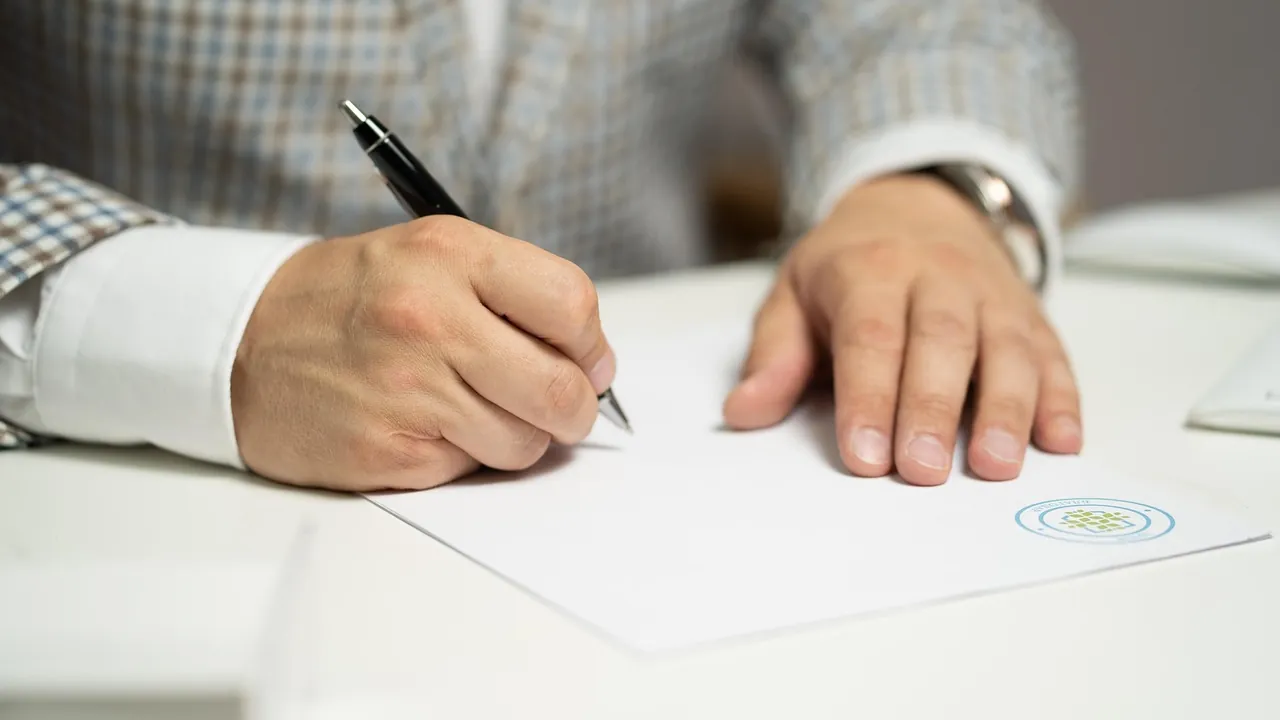 Une main remplit un document sur un bureau