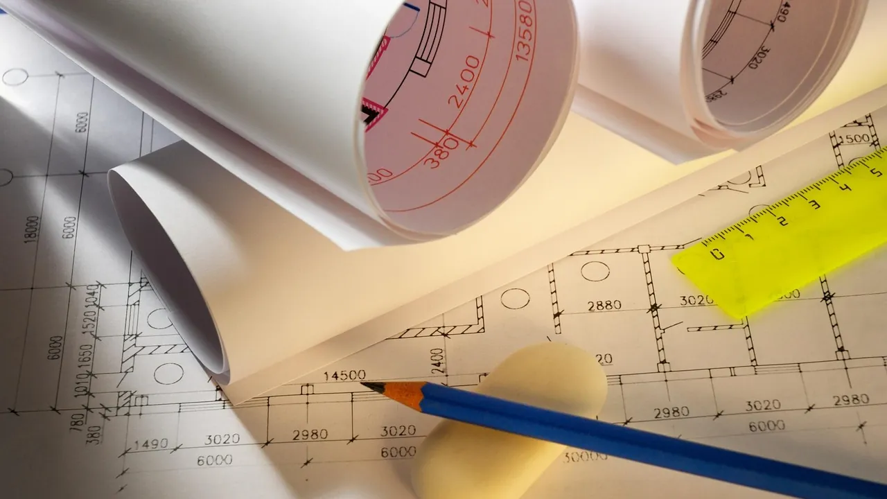 Des plans techniques, un crayon et une règle posés sur une table