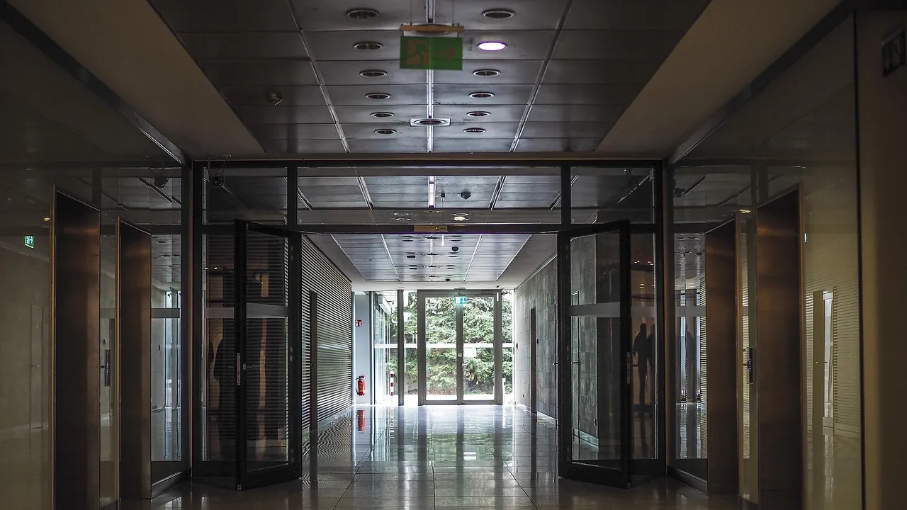 Un couloir de bureaux lumineux menant vers une porte vitrée